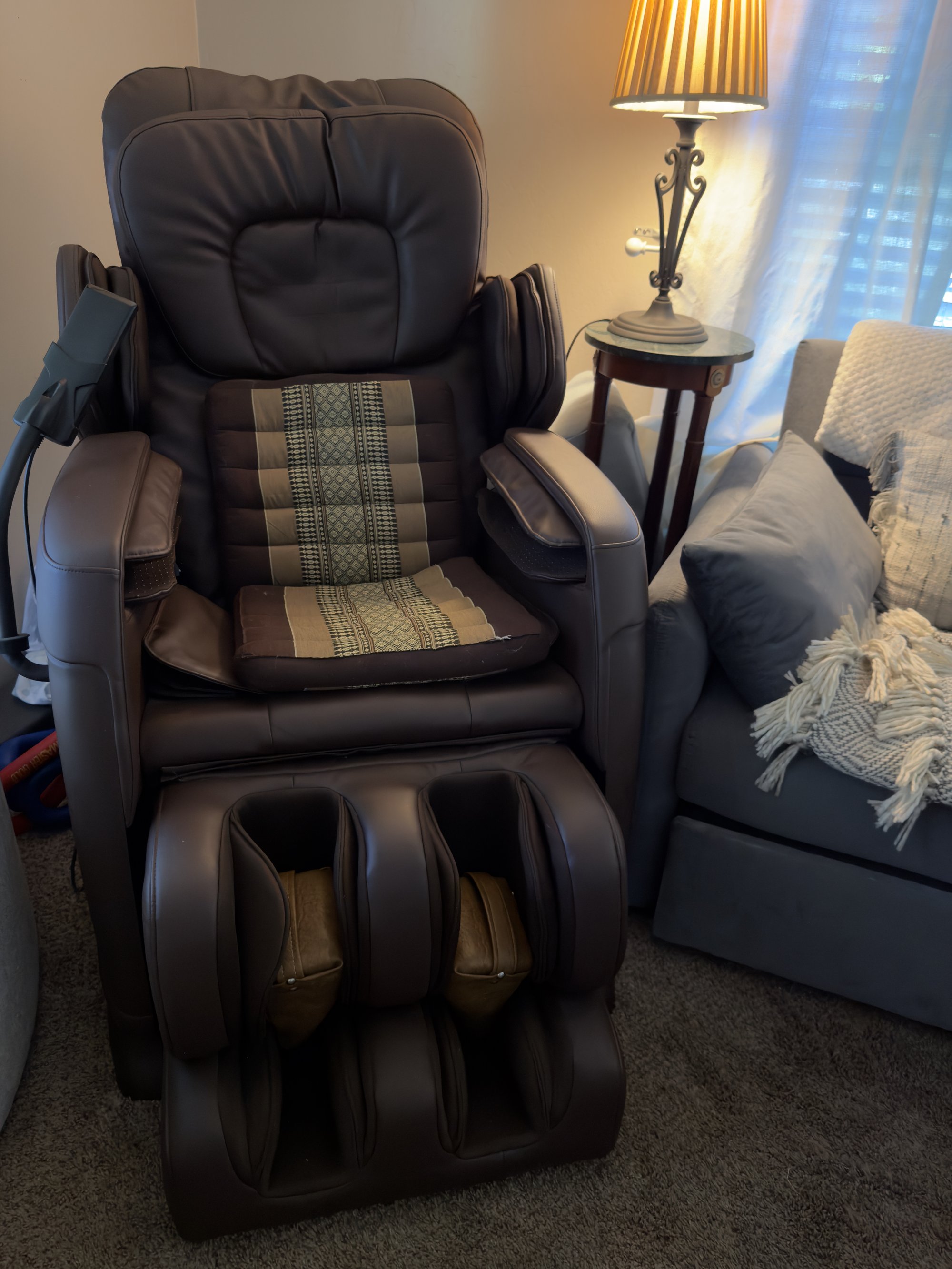 The pre-decompression massage chair: brown leather with a Thai-striped cushion and a cream knit throw draped over the headrest.